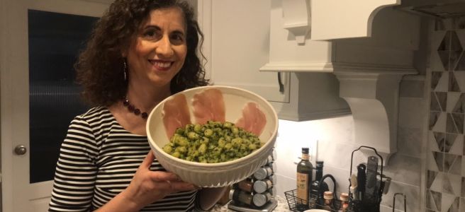 Pesto alla Genovese with gnocchi in a bowl lined with prosciutto slices, held by blogger Kathryn Occhipinti, from Conversationalitalian.french Instagram post 2021.